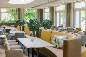 restauracja ze stołami, krzesłami i oknami w obiekcie SEETELHOTEL Ostseehotel Ahlbeck w mieście Ahlbeck