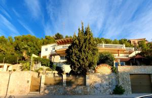 une maison avec un arbre devant une clôture dans l'établissement Ashram Villa Sunshine, à Sitges