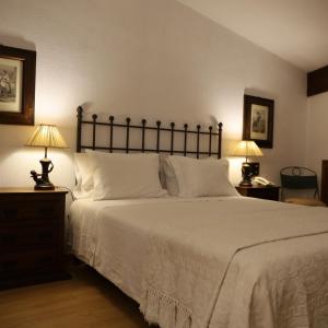 a bedroom with a large white bed with two lamps at Hotel Portofoz in Porto