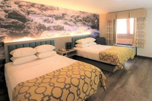 a hotel room with two beds and a painting on the wall at Baymont by Wyndham Gatlinburg On The River in Gatlinburg