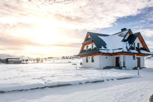 uma casa coberta de neve num campo de neve em Tatra Apartments z zewnętrznym jacuzzi em Biały Dunajec