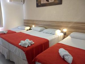 two beds in a room with red and white sheets at Pousada Aquarela Do Brasil in Maceió