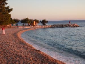 a person standing on a beach near the water at Apartmani Stipan in Brela