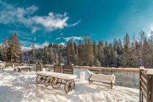 a snow covered patio with benches and tables in the snow at MK Resort (ex. Magiya Karpat) in Bukovel