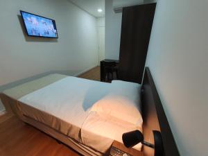 a bedroom with a bed and a tv on a wall at Hotel Carmelo in São José dos Pinhais