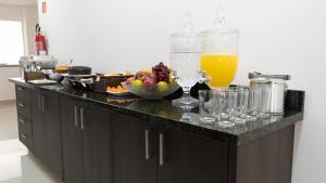 a kitchen counter with a bowl of fruit and glasses at Hotel Carmelo in São José dos Pinhais