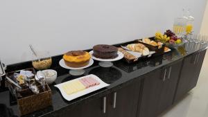 a buffet with cakes and other desserts on a counter at Hotel Carmelo in São José dos Pinhais