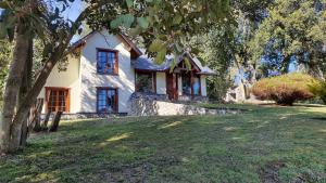 une maison blanche avec un arbre en face dans l'établissement Cabañas & Aparts Lancuyen, Villa de Montaña, à Villa La Angostura