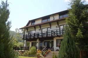 uma casa grande com escadas e árvores em frente em Pensiunea Muntele Rece em Bran