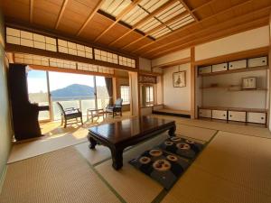 een woonkamer met een tafel en een groot raam bij Atami Onsen Guest House Megumi in Atami