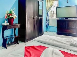 - une chambre avec un lit, une télévision et une table dans l'établissement Homestay Levida Mitra RedDoorz, à Samarinda