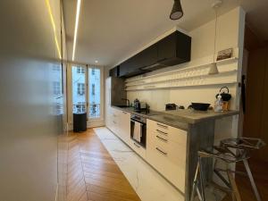 una cucina con armadietti bianchi e pavimenti in legno di RESIDENCES HARCOURT - Ile Saint Louis - PARIS a Parigi