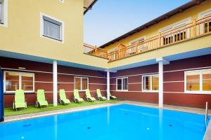 - une piscine en face d'un bâtiment avec des chaises dans l'établissement Hotel der Wolkensteinbär, à Bramberg am Wildkogel