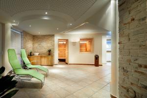 - un hall avec des chaises vertes et un mur en pierre dans l'établissement Hotel der Wolkensteinbär, à Bramberg am Wildkogel