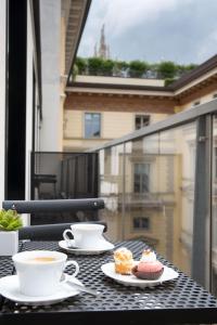 een tafel met twee kopjes koffie en gebak op een balkon bij BMORE Duomo - Luxury Apartments near Duomo in Milaan