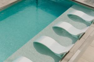 - deux chaises blanches installées dans une piscine dans l'établissement Instants Boutique Hotel - Adults Only, à Cambrils