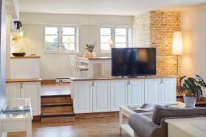 ein Wohnzimmer mit einem Flachbild-TV auf einem weißen Schrank in der Unterkunft Pierspeicher Boardinghouse in Kappeln