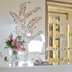 a vase of flowers on a table with a mirror at The Beverly Hills Hotel - Dorchester Collection in Los Angeles