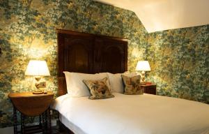 een slaapkamer met een groot bed met bloemenbehang bij Ockenden Manor Hotel & Spa in Cuckfield