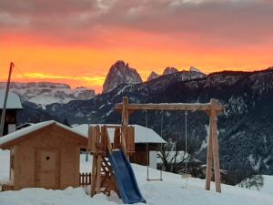 einen Spielplatz im Schnee mit den Bergen im Hintergrund in der Unterkunft Platiederhof in Lajen