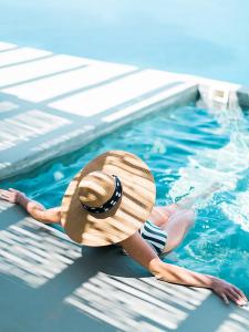 a woman in a straw hat in a swimming pool at Remezzo Villas in Imerovigli