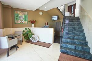 IvatoFLY INN Madagascar HOTEL - Navette GRATUITE H24 - à 300m de l'Aéroport International Ivato-Antananarivo的站在有楼梯的大厅柜台上的女人