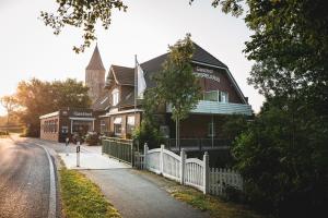 un edificio con una recinzione bianca e una chiesa di Kirchspielkrug Landhotel & Restaurant a Westerhever