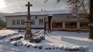 uma cruz na neve em frente a um edifício em Na Rybníčku Bohutín em Bohutín