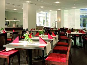 uma sala de jantar com mesas e cadeiras com guardanapos vermelhos em ibis Dresden Zentrum em Dresden