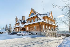 ein großes Holzhaus mit Schnee auf dem Dach in der Unterkunft Apartamenty na Leśnej in Bukowina Tatrzańska