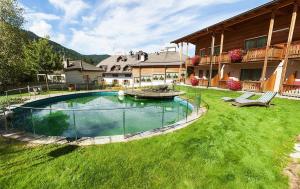 un gran patio con piscina frente a una casa en Hotel Gratschwirt, en Dobbiaco