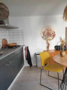 une cuisine avec une table et des chaises jaunes dans l'établissement Little Lodge Noordwijk aan Zee, à Noordwijk