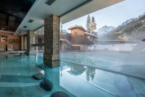 a house with a infinity pool with a mountain view at Croce Bianca Leisure & Spa Hotel in Canazei