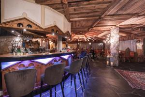 a bar with chairs in a room with wooden ceilings at Croce Bianca Leisure & Spa Hotel in Canazei