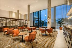 - un restaurant avec des tables, des chaises et de grandes fenêtres dans l'établissement Hyatt Place Paris Charles de Gaulle Airport, à Roissy-en-France