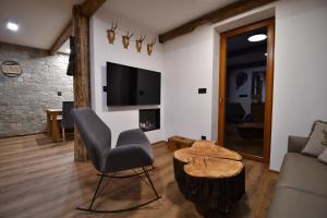 - un salon avec une chaise, une table et une télévision dans l'établissement Chalet Apartments Maštal, à Železná Ruda