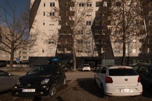 dwa samochody zaparkowane na parkingu przed budynkiem w obiekcie Roomies Zagreb w Zagrzebiu