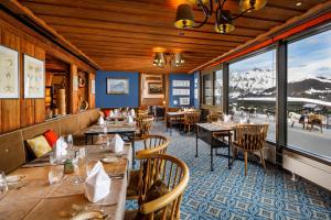 ein Restaurant mit Tischen und Stühlen mit Bergen im Hintergrund in der Unterkunft Eiger Mürren Swiss Quality Hotel in Mürren