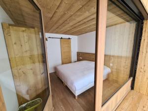 Dormitorio pequeño con cama y espejo en Chalet Le Granitic, en Les Menuires