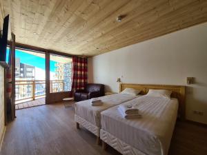 1 dormitorio con 1 cama, 1 silla y 1 ventana en Chalet Le Granitic, en Les Menuires