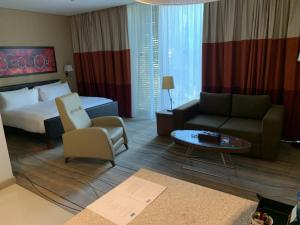 ベイルートにあるStaybridge Suites Beirut, an IHG Hotelのベッド、ソファ、テーブルが備わるホテルルームです。