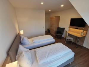 a hotel room with two beds and a desk at Hotel zur Erholung in Buxtehude