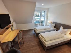 a room with two beds and a desk and a television at Hotel zur Erholung in Buxtehude