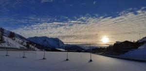 a snow covered slope with the sun in the sky at Hotel Lago Losetta in Sestriere