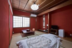 1 dormitorio con paredes rojas, 1 cama y 1 mesa en Ryokan Yamamuro, en Kanazawa