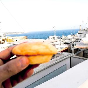 una persona sosteniendo una rosquilla frente al océano en FONTEblu B&B, en Polignano a Mare