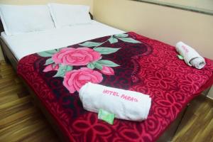 a bed with a red blanket with two towels on it at Hotel Parag in Pune