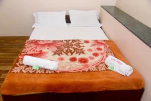 a bed with two pillows and towels on it at Hotel Parag in Pune