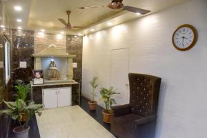 a room with a chair and a clock on the wall at Hotel Parag in Pune