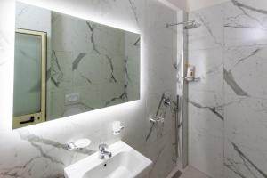 a white bathroom with a sink and a mirror at Comfortable apartment next to the beach in Durrës